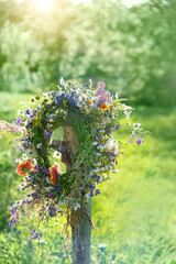 rustic wildflowers wreath in garden, sunny day. Farm lifestyle. Summer Solstice Day, Midsummer. floral traditional decor. pagan witch traditions, wiccan symbol and rituals - obrazy, fototapety, plakaty