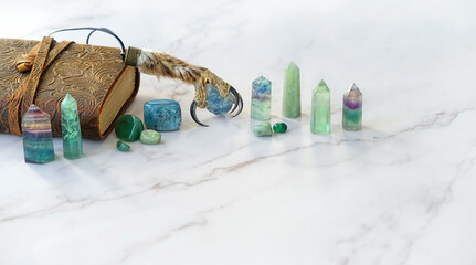 Minerals, magical amulet made of a bird's leg with claws and witch book on abstract marble...