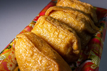 Closeup takeout Inarizushi (Inari sushi or fox sushi), a type of Sushi made with a ball of seasoned sushi rice wrapped in abura-age (a pouch of fried tofu), in supermarket food tray.