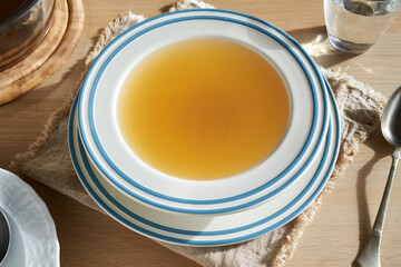 A soup bowl of beef bone broth on a table