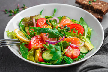 Vegetable salad with salmon and fresh herbs on a dark background.