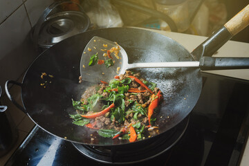 Fast thai food menu. Home cook style. Stir Fried Basil with Beef in black smoked pan on gas stove...