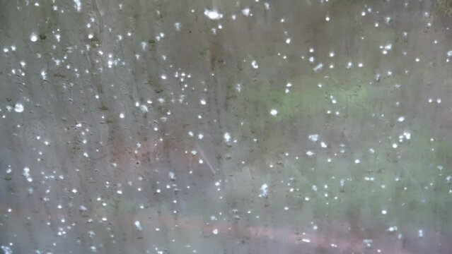 Heavy hailstorm on a paved path - the hailstones jump up from the ground.