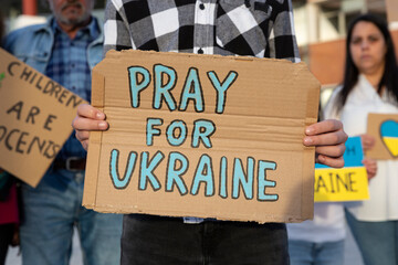 A boy demonstrator shows a cardboard sign in support of the Ukrainian people during an anti-war...