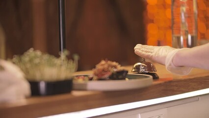 Restaurant cooking - the chef serves the dish in the distribution area and beats the bell