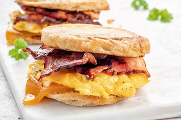 English muffin, egg, ham, and cheese breakfast sandwich on a cutting board