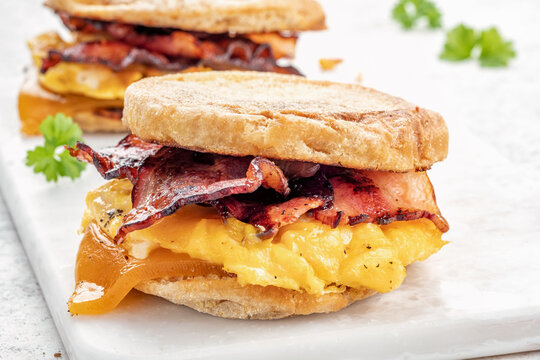 English Muffin, Egg, Ham, And Cheese Breakfast Sandwich On A Cutting Board