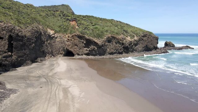 Scenic Beach With Tourist Walking On The Sandy Shore At Bethells Beach, Auckland, North Island, New Zealand - aerial descending