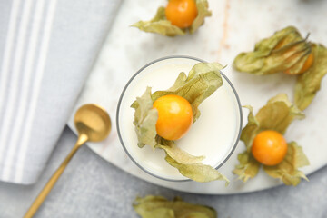 Delicious dessert decorated with physalis fruit on light grey table, flat lay