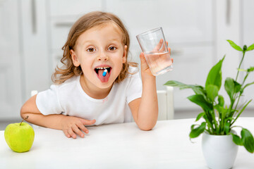 child with pill dragee on her tongue.