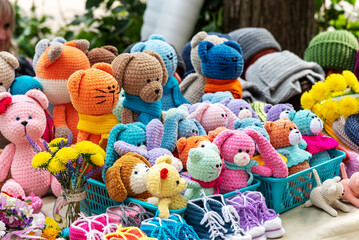 Cute soft handmade colorful knitted toys for children in blue plastic baskets put up for sale against blurred background