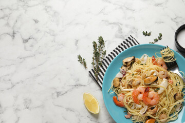Delicious pasta with sea food served on white marble table, flat lay. Space for text
