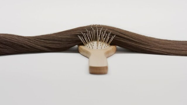 A Lock of brown hair on brush comb on grey background | Hair extensions