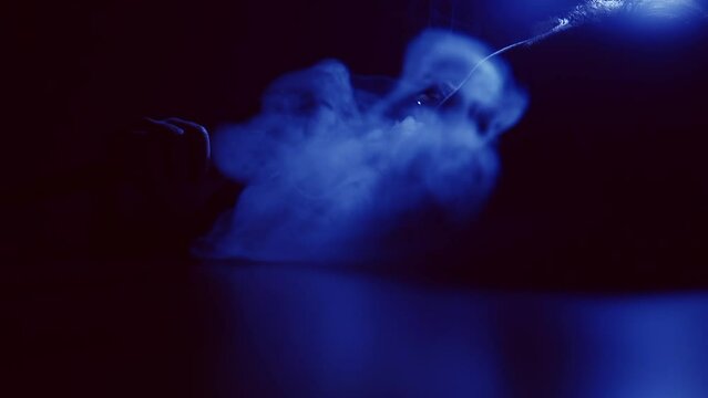 female beautiful lips smoke hookah on blue light
