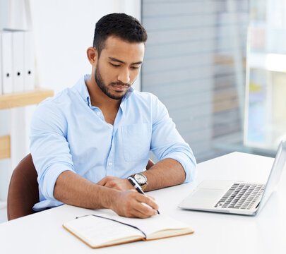 Hard work leads to success. Shot of a young businessman writing in a notebook at work.
