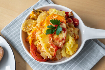 Casserole with potato, sweet potato, tomato and cheese.