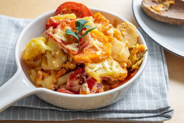 Casserole with potato, sweet potato, tomato and cheese.