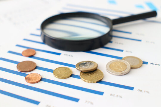 Charts, magnifying glass and coins ans sign of business in the office