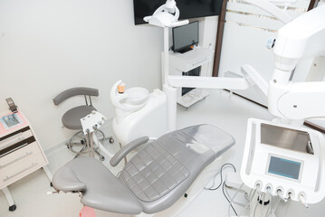 Wonderful clean dentistry office with grey seat and white equipment.