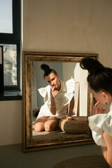 Girl in a white dress in a beige interior with a modern hairstyle

Young beautiful Ukrainian woman sitting on the floor on a round rug looks to the mirror hair gathered in a stylish hairstyle 