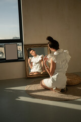 Girl in a white dress in a beige interior with a modern hairstyle

Young beautiful Ukrainian woman sitting on the floor on a round rug looks to the mirror hair gathered in a stylish hairstyle 