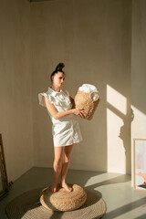 Young slender girl with a wicker basket Ukrainian woman sitting on the floor on a round rug looks to the mirror hair gathered in a stylish hairstyle has brown eyes beautiful face on her arm bracelet