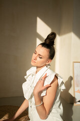 Girl in a white dress in a beige interior with a modern hairstyle

Young beautiful Ukrainian woman sitting on the floor on a round rug looks to the mirror hair gathered in a stylish hairstyle 