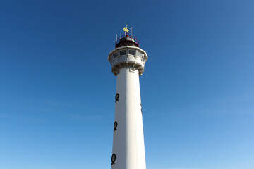 White lighthouse with blue sky on background.