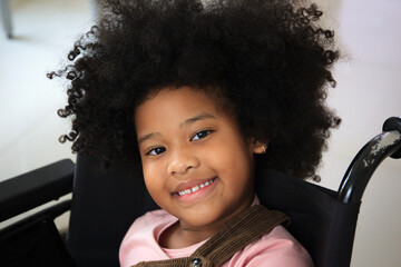 African - American ethnicity little girl resting on wheelchair while waiting to see the doctor in...