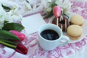 Festive spring breakfast - pink tulips, espresso coffee, cakes and paper for notes. Background for a greeting card.