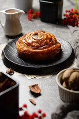cinnamon rolls .Beautiful fresh cinnamon rolls close-up on black plate  texture table. Fragrant homemade cakes, Cinnabon . Toffee sauce , Walnut , Red flower , backlight , cinnamon sticks.