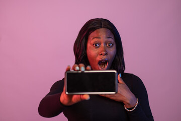 surprised young african woman showing her phone screen