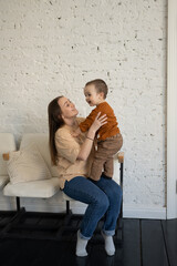 The little son and mother play in the apartment and spend time together. Family photo.