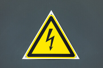 Black caution or warning electrical triangle sign or table on yellow background  on the brown painted steel wall