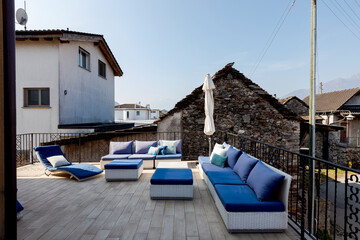 Outside terrace with small living room furnished with a sofa and chaise longue. Sunny winter day