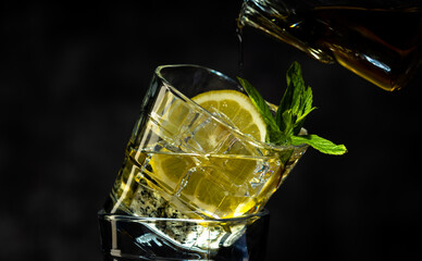 Cocktail with ice, fresh mint and a fresh slice of lemon on a dark background. Cocktails.