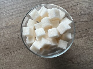 Cubes of white sugar are stacked in a sugar bowl on the kitchen table