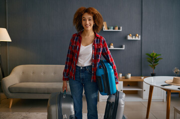 Fototapeta na wymiar Smiling woman holding baggage in living room