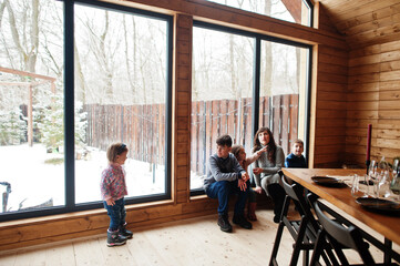 Fototapeta na wymiar Mother and kids in modern wooden house with table, spending time together in warm and love.