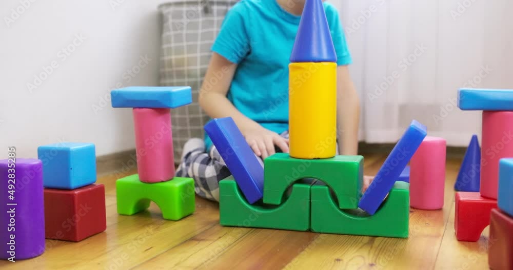 Poster a child is playing with children building blocks on floor. building a tower of cubes. educational to