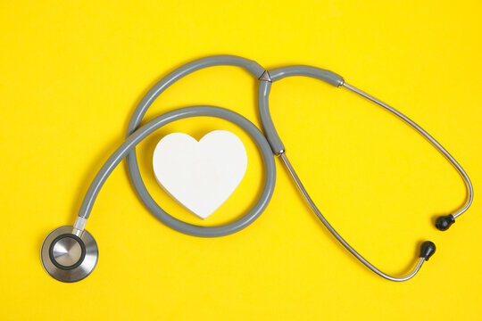 White Heart And Stethoscope On Yellow Background.Heart Disease, Medical Examination.