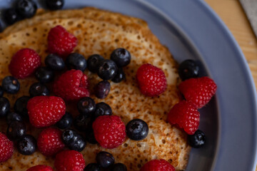 plate with pancakes and berries on a wooden table