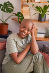 A young woman looks directly at the camera sitting on the couch at home