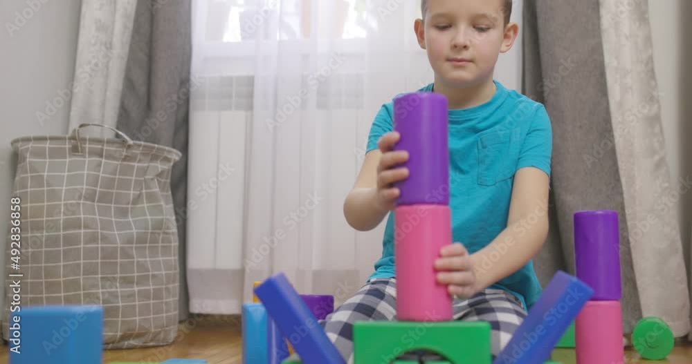 Poster a child is playing with children building blocks on floor. building a tower of cubes. educational to