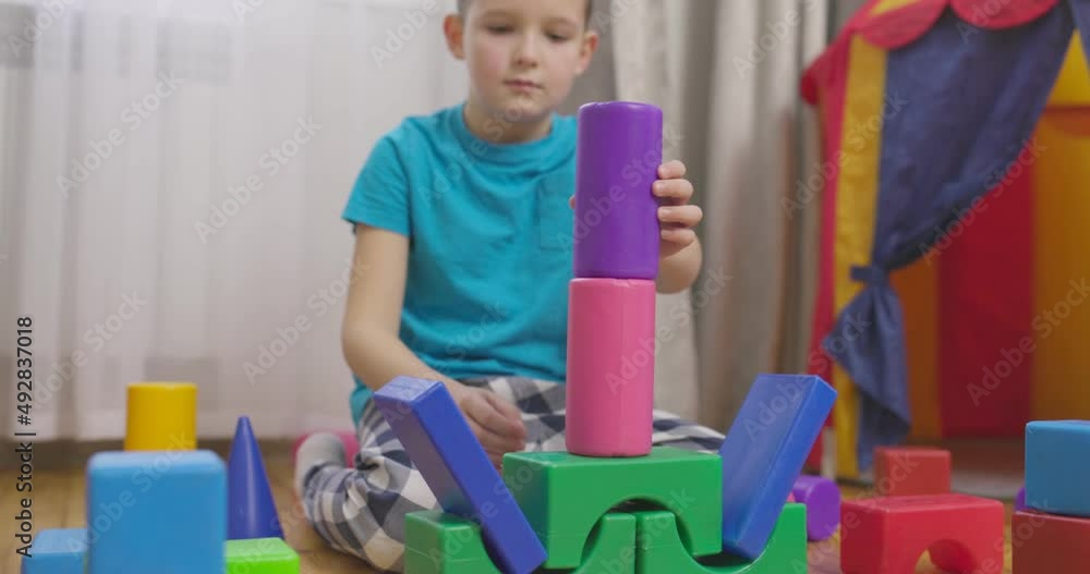 Poster a child is playing with children building blocks on floor. building a tower of cubes. educational to