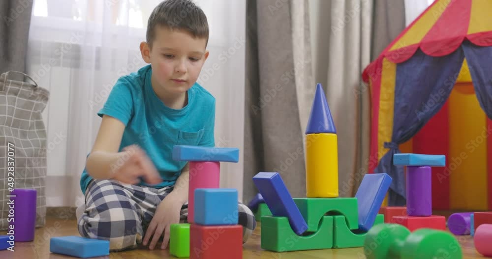 Poster a child is playing with children building blocks on floor. building a tower of cubes. educational to