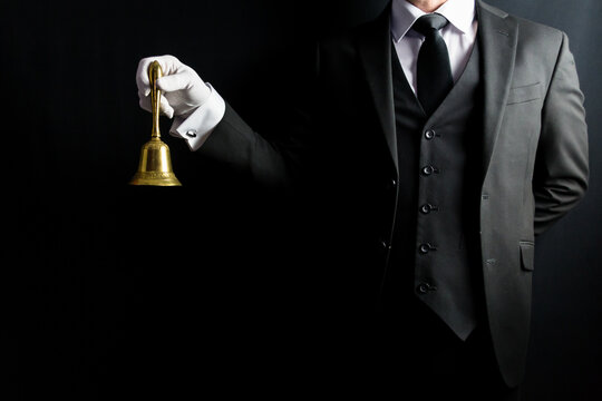 Portrait of Butler in Dark Formal Suit and White Gloves Holding Gold Bell. Professional Hospitality and Courtesy. At Your Service.