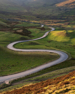 Long winding curved road leading through British valley below Mam Tor in the Peak District. Conceptual landscape backgrounds.