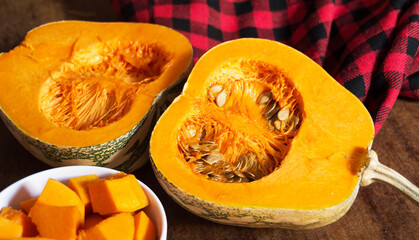 Raw pumpkin cut in half and chopped pumpkin in the bowl