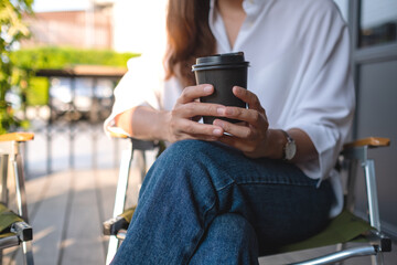 Closeup image of a woman holding a paper cup of hot coffee